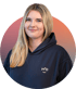 Junge Frau mit blondem Haar und dunkelblauem Hoodie lächelt.