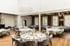 Großer, heller Festsaal mit runden Tischen, weißen Tischdecken, Blumenarrangements und grauen Stühlen.
