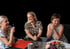 Drei Frauen sitzen lächelnd an einem Tisch; Text "Das Team" oben links.