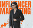 Woman in black blazer and sunglasses, with "INFLUENCER MARKETING" in orange text above her.