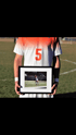 Ein Spieler mit Trikot Nr. 5 hält ein gerahmtes Foto von sich selbst auf einem Fußballfeld.