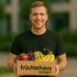 Lächelnder Mann hält eine Kiste mit frischem Obst und dem Logo "früchtehaus stuttgart".