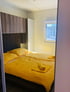 Schlafzimmer mit zwei Einzelbetten, gelben Bettdecken und Handtüchern sowie einem Fenster.