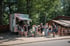 Menschen stehen vor einem rosa-grünen Imbisswagen mit der Aufschrift „Die kleine Crêperie“ im Wald.