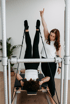 Eine Trainerin leitet eine Frau beim Pilates-Training am Reformer-Gerät an, während diese ihre Beine senkrecht nach oben streckt.