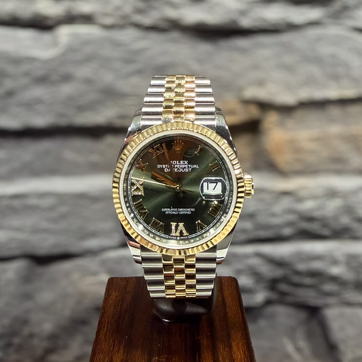 Zweifarbige Rolex Datejust Uhr mit grünem Zifferblatt, Goldlünette und römischen Ziffern, auf Holzständer.