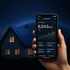 Hand hält Smartphone mit Solar-App vor Haus mit Solaranlage bei Nacht.
