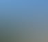 Ein Feldweg führt durch grüne Weinberge und Hügel unter blauem Himmel.