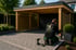 Handwerker der Firma Sparrenburg Garten- und Landschaftbaumontiert ein hölzernes Flachdach-Carport auf einer gepflasterten Einfahrt in Paderborn.