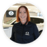 Frau mit rotem Haar in schwarzem Mazda-Hemd lächelt in einem Autohaus.