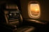 Schwarzer American Express Platinum Kreditkarte auf einem Business-Class-Flugzeugsitz; Sonnenuntergang durch das Fenster.