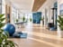 Moderner Physiotherapie-Raum mit Trainingsmatten, Gymnastikbällen, Behandlungsliegen und Sprossenwand bei hellem Tageslicht.