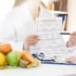 Nutritionist showing meal plan with fresh fruits

