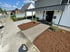 Modernes Einfamilienhaus mit Carport, Rindenmulch-Beeten und einem Kiesweg zum Eingangsbereich.