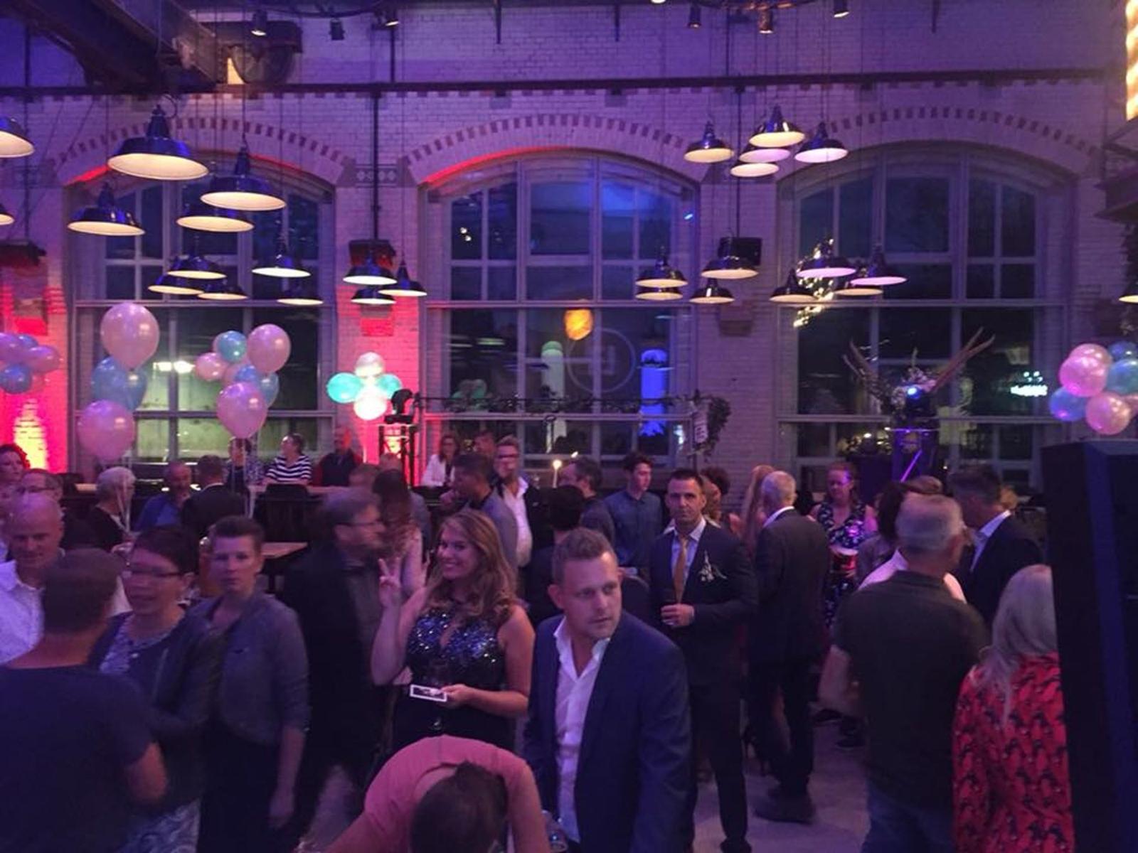 Collega's in pak en jurk op een bedrijfsfeest onder de verlichting van Superfuif