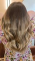 Rückansicht von langem, gewelltem Haar mit Balayage-Farbverlauf von Dunkelblond zu Hellblond.