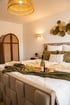 Schlafzimmer mit großem Bett, Weinflasche, Glas und Trauben auf einem Tablett.