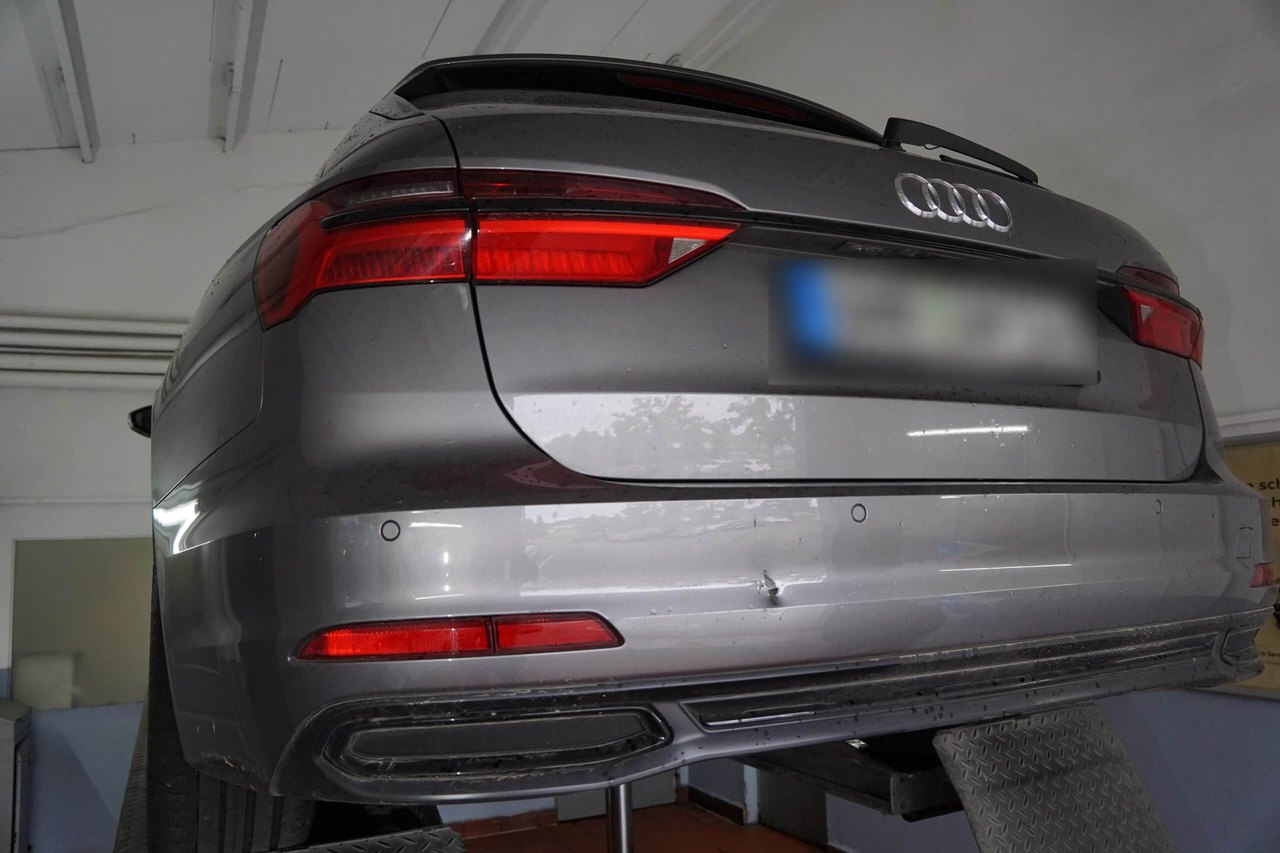 Grauer Audi mit Delle am hinteren Stoßfänger auf der Hebebühne: Schadenhöhe für ein Unfallgutachten einschätzen