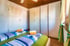 Zwei Einzelbetten mit blauen und grünen Bettdecken, ein weißer Schrank, eine Tür und ein Fenster mit Vorhängen in einem Schlafzimmer.