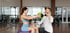 Woman passes medicine ball to man, focusing on exercise for sciaica