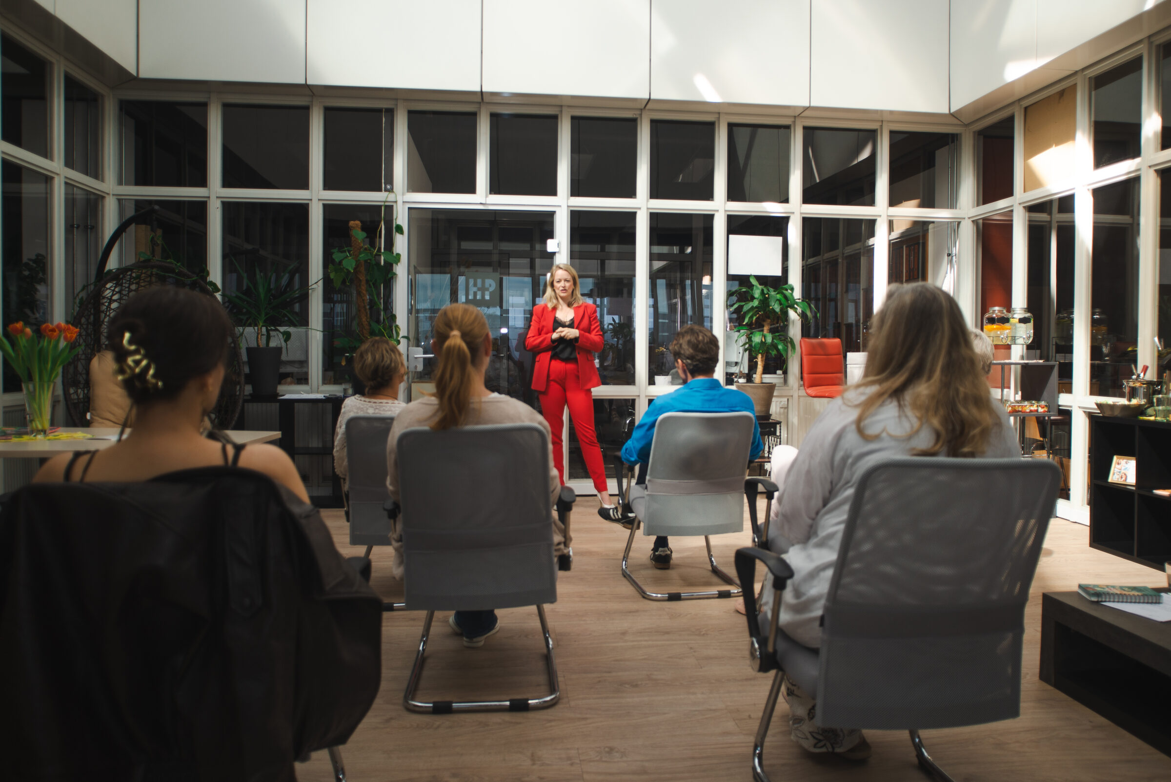 Mandy-Marie Mahrenholz im roten Anzug beim Leadership-Impuls vor den Teilnehmerinnen von The Art of Presence
