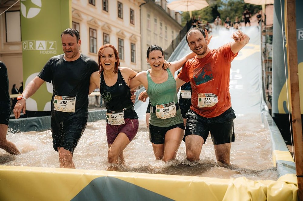 Teilnehmer beim Grazathlon von Beat the City durchqueren das Wasser-Hindernis mitten in der Grazer Altstadt