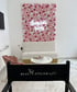 Sitzbereich mit rosa Blumenwand, Neonlicht "Beauty Atelier by Fadia" und schwarzem Stuhl mit Logo.