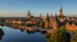 Stadtansicht von Lübeck mit dem Holstentor, der Trave und Kirchtürmen bei Sonnenuntergang.