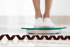 Person stepping on the scale to track weight loss progress.