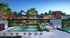 Modern apartment complex with a large swimming pool, wooden deck, sun loungers, and lush green landscaping.