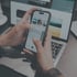 Hände bedienen ein Smartphone mit einer Galerie-App vor einem geöffneten Laptop.