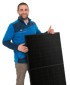 Mann im blauen Fleece-Pullover hält ein schwarzes Solarmodul und zeigt einen Daumen hoch.