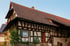 Ein traditionelles Fachwerkhaus mit Ziegeldach, braunen Holzbalken und weißen Wänden unter blauem Himmel.