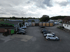 Drohnenansicht eines Industriehofs mit mehreren Gebäuden, geparkten Transportern und LKW-Anhängern.