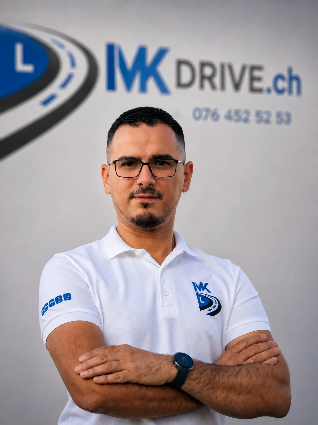 Mevljudin, Fahrlehrer von MK Drive, vor der Wand mit dem MK-Drive-Logo