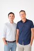 Zwei Männer, Herr Sergej Samsonow und Herr Uwe Schulz, die in Hemden stehen nebeneinander vor weißem Hintergrund und blicken in die Kamera.