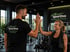 Trainer und Kundin geben sich im Sportivo Gesundheitscenter Gnarrenburg ein High Five vor Hantelregalen.