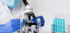 Scientist leans forward at microscope, studying medicine for sciatic pain