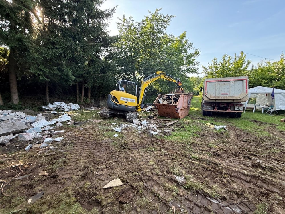 Freigelegtes Grundstück nach dem Abriss mit Bagger und Container
