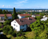 Weißes Einfamilienhaus an kleinem Bach mit grasbewachsenen Ufern, darüber Schriftzug "RESERVIERT"