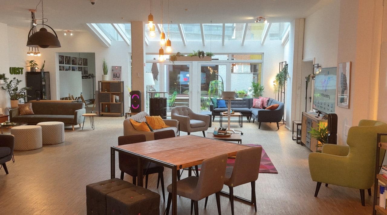 Offener Loftbereich der Heldraumstation mit langem Tisch, Oberlicht und Lounge