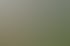 Eine Hand hält einen roten und weißen Stofffußball vor einer unscharfen Dartscheibe im Garten.