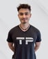 Junger Mann in T-Shirt mit "TP Personal Training" Logo, Hände hinter dem Rücken.