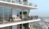Modern apartment building balconies with glass railings, outdoor furniture, and potted plants, overlooking a city.
