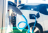 Ein weißes Elektroauto wird an einer Ladestation mit blauem Kabel aufgeladen.