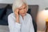A woman holds her head in her hands, experiencing pain.









