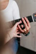 Nahaufnahme einer Hand mit Fingerschienen-Bandage beim Greifen von Akkorden auf einem Gitarrenhals.