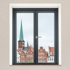 Blick aus einem Fenster mit anthrazitfarbenem Rahmen auf eine historische Stadt mit rotem Kirchturm und Giebelhäusern.
