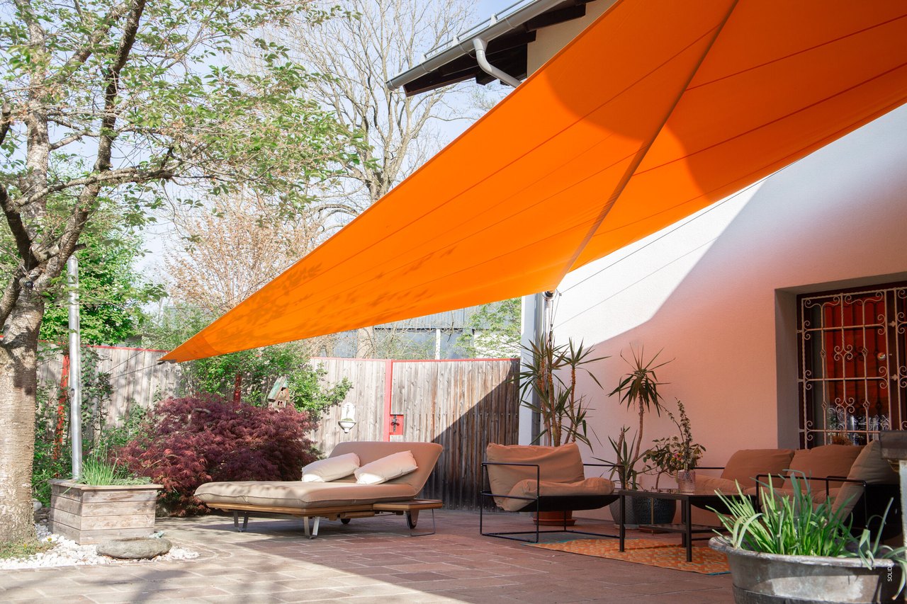 Oranges Sonnensegel spannt sich über die Terrasse
