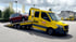 Gelber ADAC Abschleppwagen zieht ein rotes Auto, mit "HESS" und Telefonnummer auf der Seite.